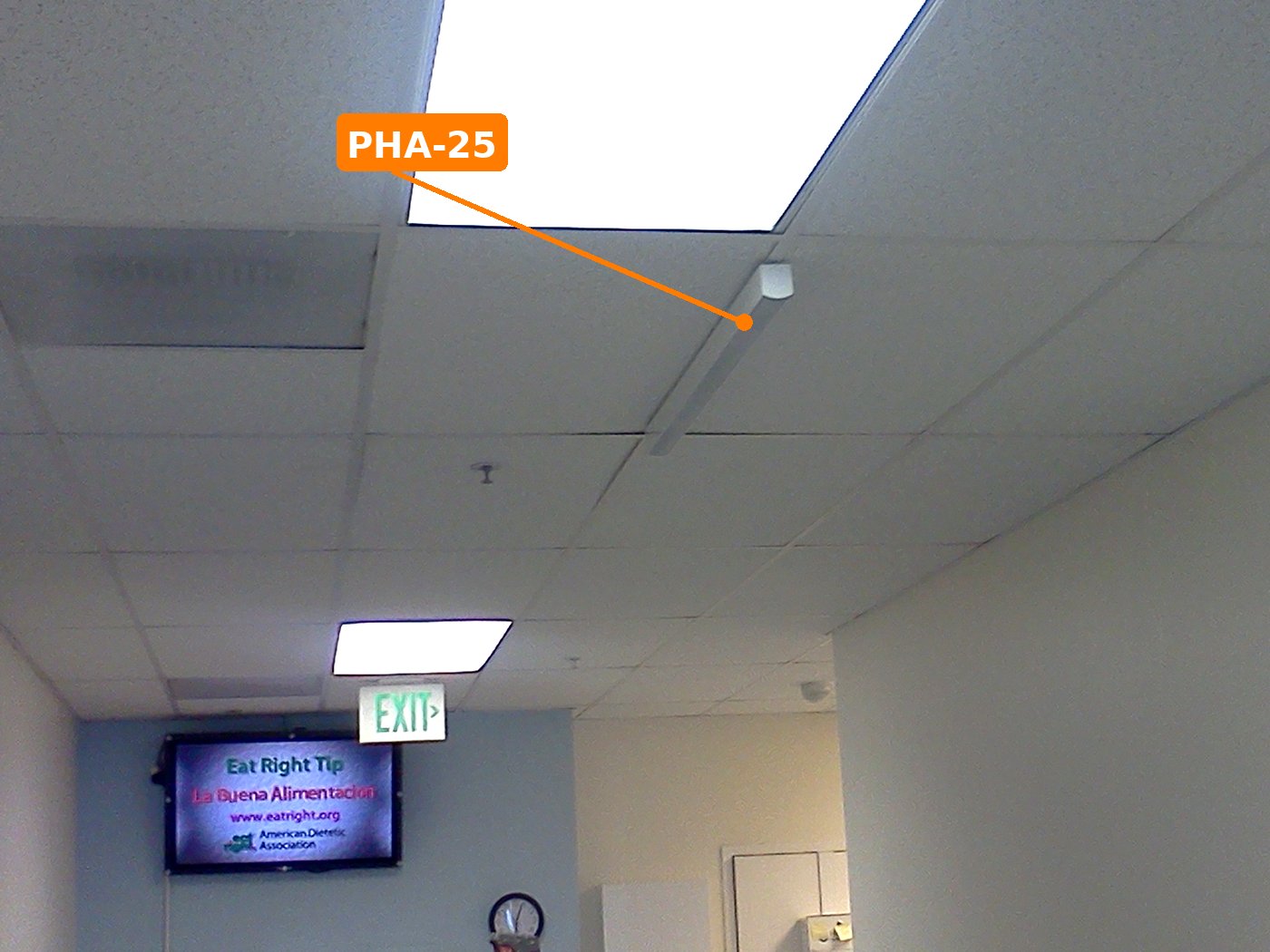 PHA-25 on the ceiling grid above a clinic waiting area, signage display below